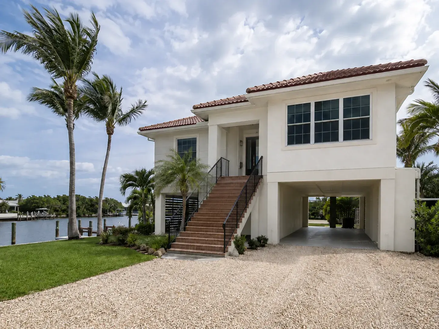 A Florida canal-front home built on an elevated stem-wall foundation with parking beneath and steps to the front door